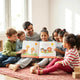 Children and a parent reading an open illustrated book on a rug with learning materials nearby