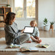 Parent and child reading kids’ e-books on a tablet in a cozy room with a few picture books nearby