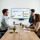 Manager and team reviewing a task workflow on a shared screen in a modern meeting