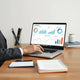 Business professional reviewing analytics charts on a laptop dashboard at a desk