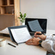 Writer reviewing laptop drafts and handwritten notes to make AI content sound natural and authentic