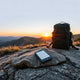 Backpack and e-reader on a rock in a mountain sunrise landscape