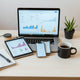 Laptop showing unlabeled e-commerce analytics charts on a clean desk with tablet and phone