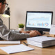 Agency owner reviewing laptop dashboard with revenue trend charts and client proposal folders on a clean desk