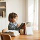 Child reading an e-book on a tablet at a desk with age-appropriate books nearby
