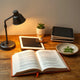 Cozy reading scene with an open book, e-book devices, and a small fox-themed bookmark on a wooden desk.